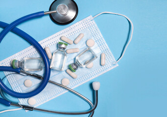 Medical concept. stethoscope, face mask, medical gloves, pills, ampoules, on a blue background. close-up.