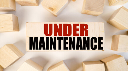 Under Maintenance. text on a piece of wood. on a white background