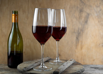 Two glasses of red wine. The bottle of wine is on the table. Wine background. Still life. Alcoholic drink in a glass. Wooden background