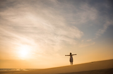 Fototapeta na wymiar Freedom and happiness. Along young woman on sand enjoying sun, nature