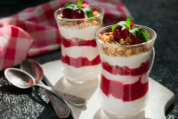 Two glasses with fresh raspberries and cream cheese on a black background. Healthy homemade organic dessert.