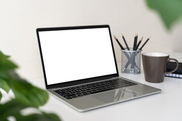 Fototapeta premium Laptop computer with blank screen for mockup on modern contemporary workspace desk with coffee cup and office supplies. Home office workplace.