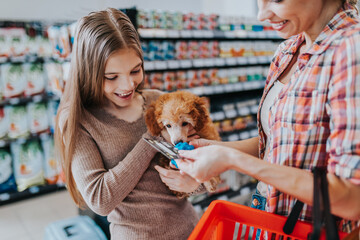 Mother and daughter with their poodle puppy in pet shop.
