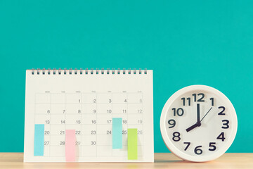 close up of calendar and alarm clock on the table with green background, planning for business meeting or travel planning concept