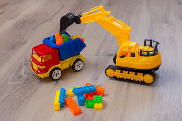 Fototapeta premium Plastic toy truck and excavator. Multicolored children's toys. Game.