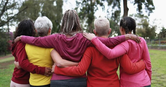Multiracial women hugging each other - Back view of multi generational people together outdoor at park 