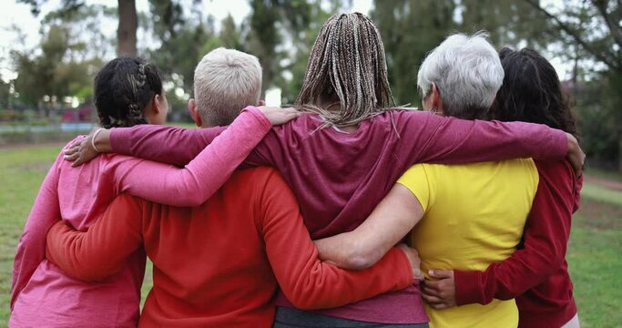 Multiracial women hugging each other - Back view of multi generational people together outdoor at park 
