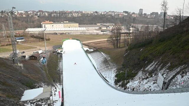 Jumper flying over ski jump ramp. The skier is then airborne until landing on the landing slope. Out-run on the bottom. Middle size ski jump in Kranj, Slovenia