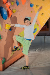 Hübsche, nette, freudliche Jungen und Mädchen beim Klettern, Bouldern. Die Kinder, 8 bis 12 Jahre alt, freuen sich Hallensport zu treiben und auszutoben. Fitness, Gesundheit, Spass für die Familie.