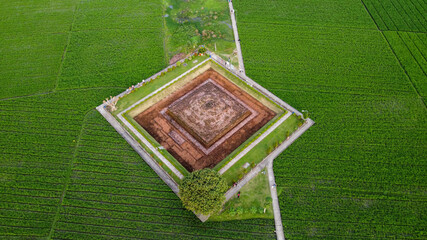 Aerial drone view of Blandongan temple at Karawang and surrounded by green grass with noise cloud....