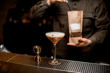 view of beautiful glass with frothy espresso martini cocktail decorated with coffee bean