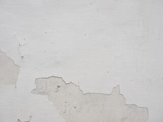 White wall with peeling pieces of the wall.