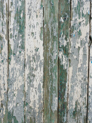 Old wooden planks painted with peeling white and green paint.