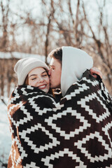 Beautiful couple in love on a winter picnic, wrapped in a blanket