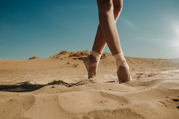 Ballerina in pointe shoes dancing in the desert
