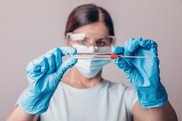 Specialist holding test kit for PCR testing virus covid19. Coronavirus COVID-19 swab test kit, PPE protective mask and gloves, tube for taking OP NP patient specimen sample, DNA RNA protocol process