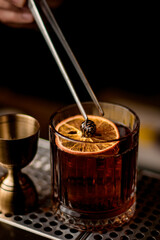 beautiful close-up view on glass with cocktail decorated with orange slice and small pine cone