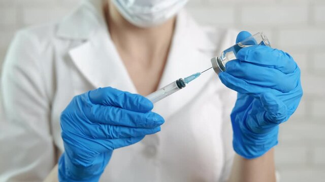 Filling up a syringe with vaccine. A nurse stay in the room and filling up a syringe with a liquid from ampoule.