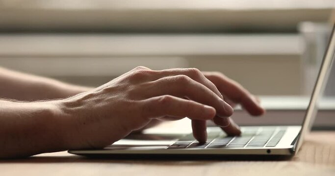 Close up male hands typing message on laptop. Businessman sit at desk texting e-mail, correspond to client remotely, writes text on portable wireless pc keyboard, modern electronic tech usage concept