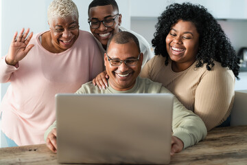 Happy black family having fun doing video call using laptop at home during corona virus outbreak - Technology and communication concept