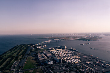 A horizontal aerial view of the Tokyo Gate Bridge in Tokyo Bay from a helicopter at sunset in springtime