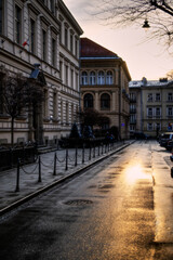Fototapeta na wymiar Shot of sunset over Studencka Street in Cracow. Beautiful golden glow reflected on wet road.