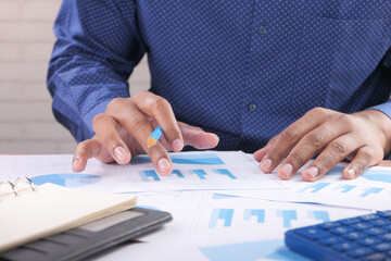 man hand with pen analyzing bar chart on paper 