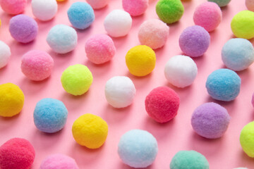 Colorful soft pom pom balls on pink background