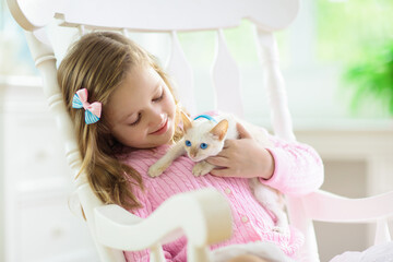Fototapeta premium Child playing with baby cat. Kid and kitten.