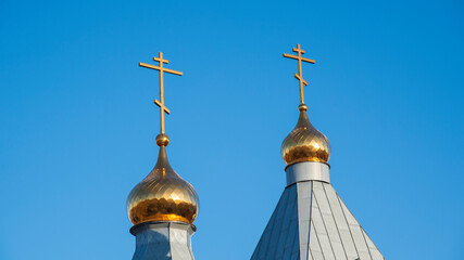 Fototapeta na wymiar Golden domes with Christian crosses on a blue sky background. The concept of the Church