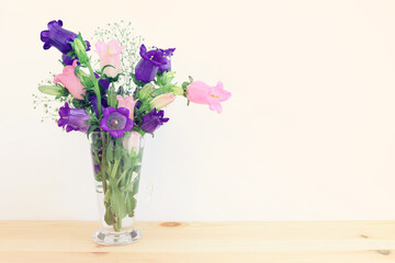 spring bouquet of purple and pink bell flowers over purple wooden background