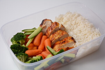 Healthy balanced lunch boxes. Grilled chicken, carrots, cucumbers, broccoli, and white rice. Lunch boxes with food ready to go for work or school. Office food lunch concept