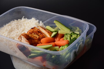 Healthy balanced lunch boxes. Grilled chicken, carrots, cucumbers, broccoli, and white rice. Lunch boxes with food ready to go for work or school. Office food lunch concept