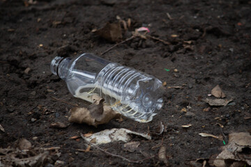 Empty plastic beer bottle on the street, trash everywhere 