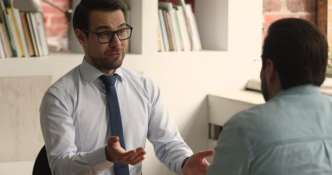 Two satisfied business men sit at desk discussing commercial deal, shaking hands after effective successful negotiations in office. HR manager and job interview recruiting meeting, employment concept