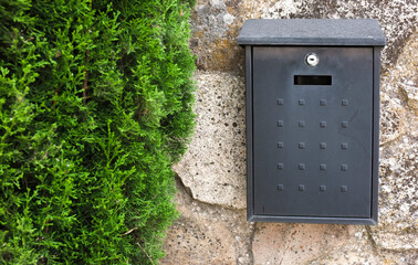 Black metal mailbox attached on cottage wall house