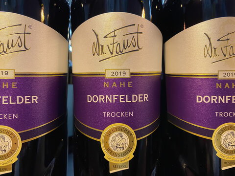 Viersen, Germany - March 1. 2021: Closeup of dornfelder wine bottles in shelf of german supermarket (focus on center)