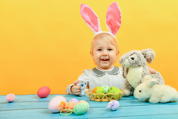 Obraz na płótnie Canvas Little girl hugs and kisses Easter bunny on a yellow background.
