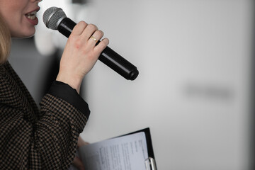 Presenter Giving Presentation and Moving Hand Holding Projector Remote Control. Corporate Business Marketing Manager and Sales Pitch. Speaker in Business Meeting Room Holding Microphone Next to Screen