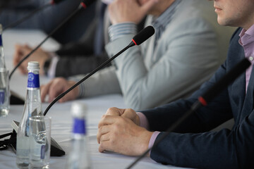 Businessman giving interview at table with microphones, closeup. Journalist conference