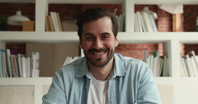 Head shot young confident man applicant sit indoor look at camera start videocall, communicates with HR manager remotely, pass job interview by videoconference, web cam view. Video call event concept