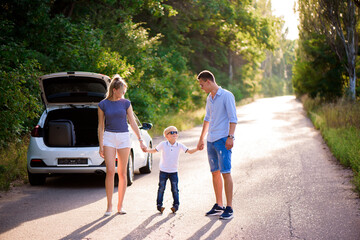 Young family travels by car. Dad, mom and son take a break from driving a car and walk.