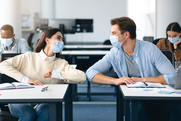 Diverse students wearing face masks greeting and bumping elbows