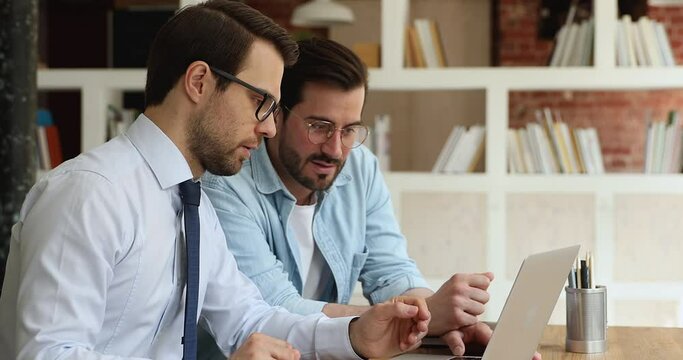 Millennial colleagues discuss project on laptop, share ideas and skill express opinions and solutions. Client ask questions to manager about online presentation during formal meeting in company office