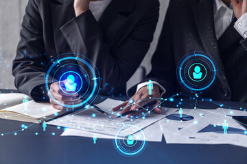 Two HR specialists analyzing the market of freshers to boost the intern program at international consulting company. Hiring new talented crew. Social media hologram icons. Women in business.