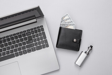 Laptop, wallet and vaping device on a gray background. Flat lay