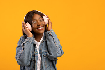 Joyful african american lady listening to music, using wireless headset