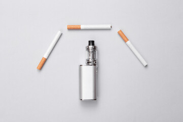 Vaping device and cigarettes on gray background. Alternative to smoking. Top view