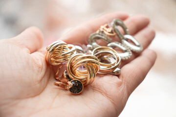 jewelry made of red and white gold: rings, earrings lie in a woman's palm. Women's things,...