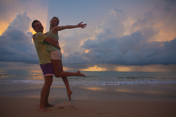 Fototapeta premium The image of silhouette of two people in love at sunset in Thailand